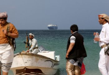 FILE PHOTO: Armed men stand on the beach as the Galaxy Leader commercial ship, seized by Yemen’s Houthis last month, is anchored off the coast of al-Salif