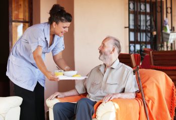 elderly senior being brought meal by carer or nurse